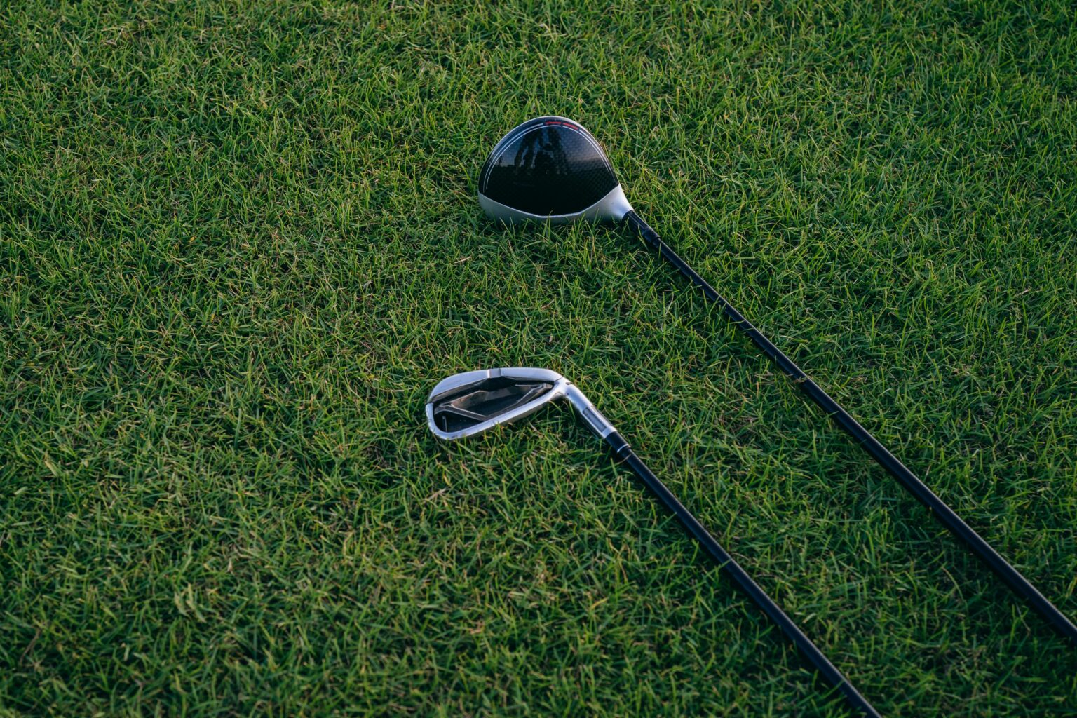 A close-up view of two golf clubs resting on neatly manicured grass, perfect for golf enthusiasts.